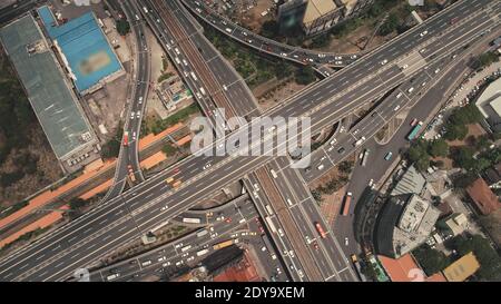 Cross highway top down at Philippines cityscape aerial. Cars, buses, vans, trucks ride at traffic roadway of Manila city. Urban scenery with buildings, skyscrapers, cottages at road Stock Photo