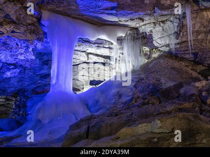 Entrance to ice cave with plenty of icicles. Slope of the mountain inside a fantastic cave. Kungur In The Urals, Russia Stock Photo