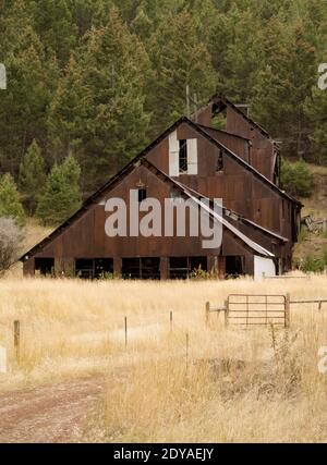 A rusty, corrugated steel building near the Henderson Creek Mine, on Henderson Creek, southwest of Hall, in Granite County, Montana Stock Photo