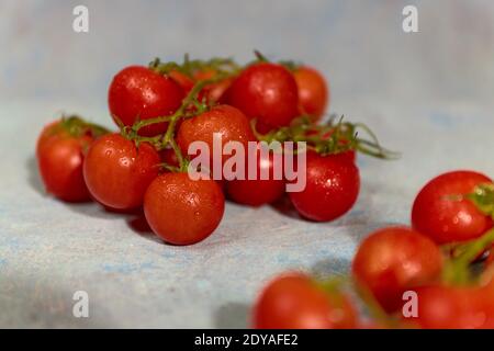 Fresh grape tomatoes with spinach Leaves on white hand painted background. Vegan veggies diet food. Herb, red tomatoes, cooking concept. Stock Photo