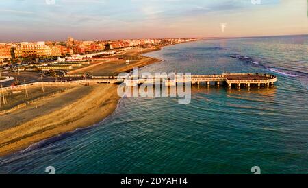 Sunset Rome aerial view in Ostia Lido beach over blue sea and brown sandy beach, beautiful coast line with pedestrian pier a landmark of tourist and c Stock Photo