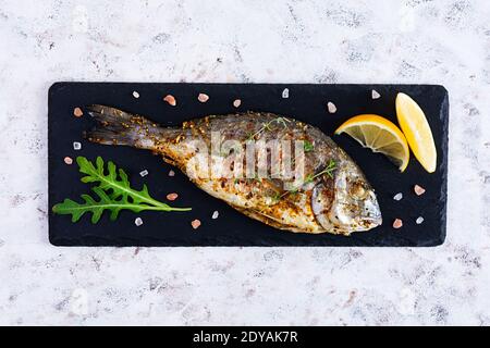 Grilled dorado fish on white background. Roasted seafish with spice and herbs Stock Photo