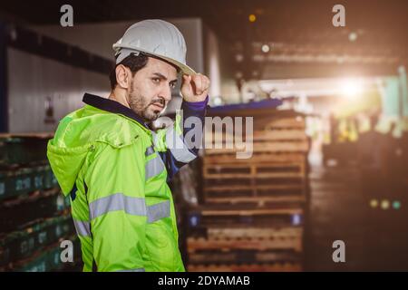 Portrait smart Latin worker in cargo port logistic warehouse standing confident with safety suit. Stock Photo