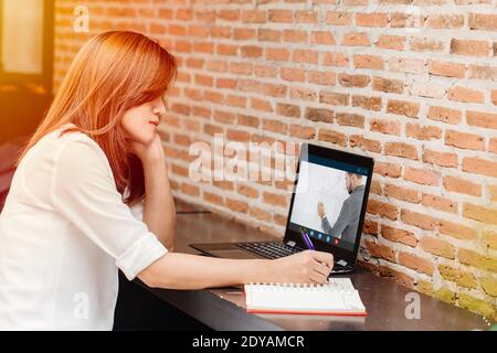 e-learning concept, woman watching teacher live internet video streaming lecture from laptop computer screen at cafe. Stock Photo