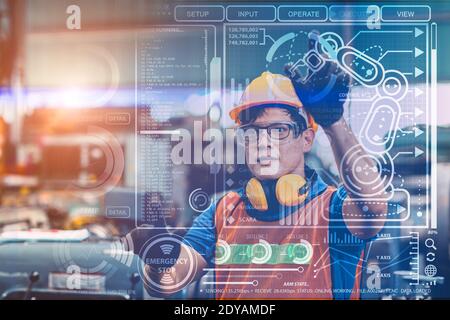 Smart engineer worker using advance technology visual holographic air screen to program and control robotic arm for automated production in modern fut Stock Photo