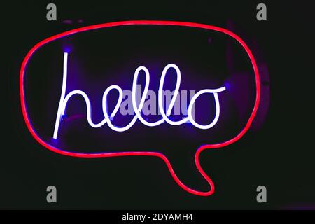 Neon night light greeting word sign text "Hello" on black background. Stock Photo