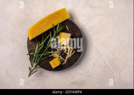 Rosemary twig and parmesan cheese on a cutting board on light textured background, top view, copy space Stock Photo