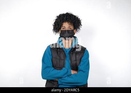 A portrait of a casual afro young man in a black medical mask on a white background - new normal Stock Photo