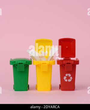 three multi-colored plastic containers on a pink background, the concept of correct sorting of garbage for further recycling Stock Photo