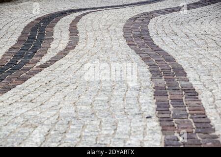Background image of old cobblestone road backlit with low sunlight. Stone texture close up. Small pebbles on the road. Stone path Stock Photo