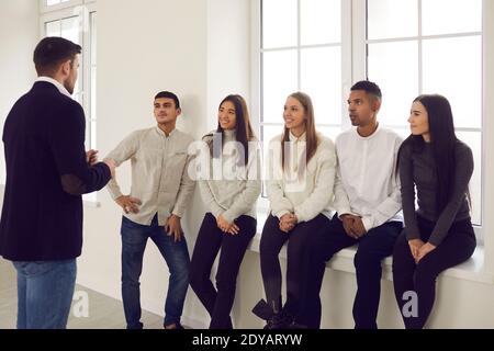 Experienced businessman and business coach giving a talk to group of happy students Stock Photo