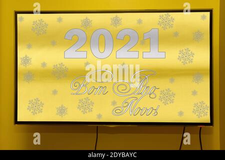 New Year's greetings in Brazil and Portugal in trending colors of 2021 means Happy New Year. Text on a modern TV screen hanging on the wall. Stock Photo