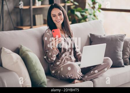 Photo of nice optimistic girl sit write telephone hold laptop wear pijama at home Stock Photo