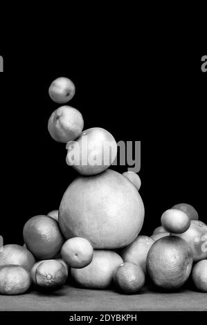 Monochrome falling tower of citruses, oranges, pomelo, limes, tangerines and grapefruits isolated on black background Stock Photo