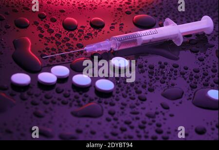 Drug concept, addiction. Syringe and pills on dark background with water drops. Night life. Neon light Stock Photo