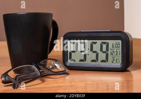 23:59 new years eve 2020 ending clock. Glasses and cup on wooden table. Happy new year. Stock Photo