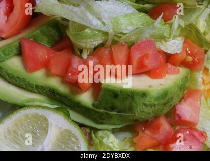 Close up of the sliced avocado with tomato, lettuce and lime Stock Photo