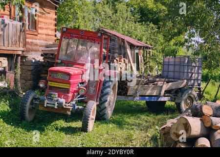Old red tractor and trailer on a farm of Breb, in the Maramures area of Romania, where people still live a simpler way Stock Photo