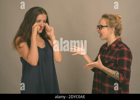 Two young beautiful woman friends against gray background Stock Photo