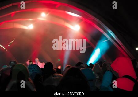 Blurred bokeh Light on a dark background. Defocused Image of an Illuminated outdoor stage area at Night. Unfocused stage lights and the crowd at the c Stock Photo