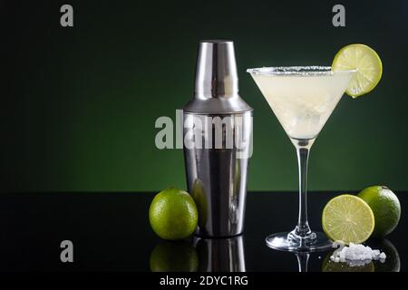 Typical Mexican margarita cocktail with lime slice ice and cocktail shaker on  black and green background. with copy space Stock Photo