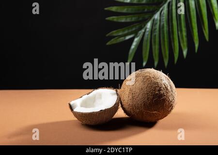 Split coconut with palm leaf in the background. Stock Photo