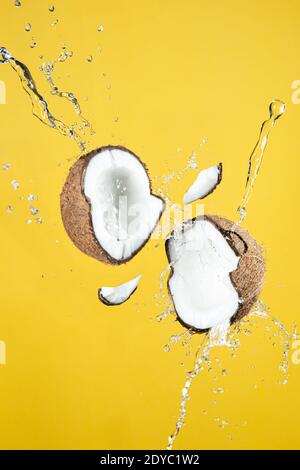Floating coconut breaking with coconut water splash, On yellow background. Stock Photo