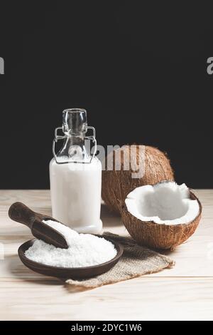 Coconuts, coconut milk and grated coconut on dark background. Stock Photo
