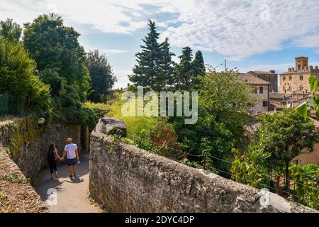 Elevated view of the old uphill town of Volterra with a couple of young lovers walking hand in hand in summer, Pisa, Tuscany, Italy Stock Photo