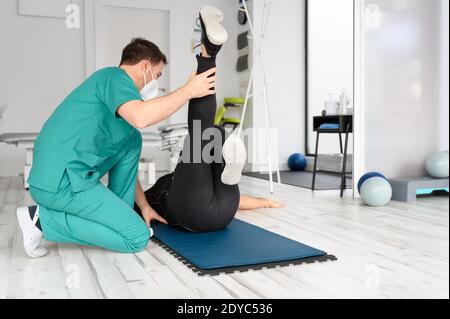 Physiotherapist assisting man in performing exercise on mat. High quality photo Stock Photo