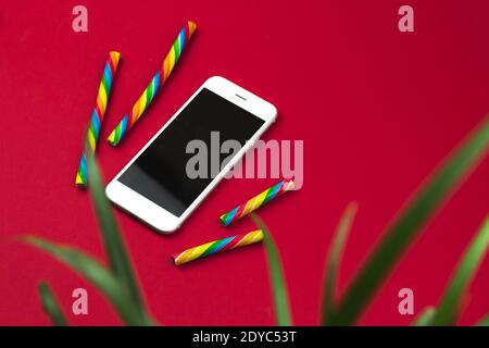 Conceptual desktop with smartphone and houseplant on red background and sweets, minimal design photo Stock Photo