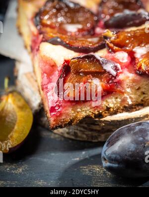 rustic plum cake on wooden background with plums around Stock Photo