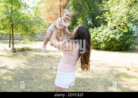 happy harmonious family outdoors. mother throws baby up, laughing and playing in the summer on the nature Stock Photo