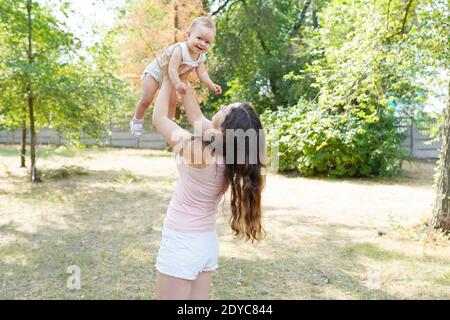 happy harmonious family outdoors. mother throws baby up, laughing and playing in the park Stock Photo