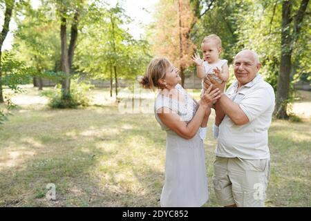 grandparents and baby grandchild walking in nature park, copy space Stock Photo