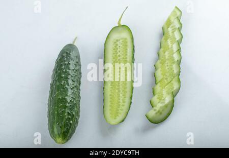 Close-up of whole fresh green cucumbers and slices isolated on white background. Stock Photo