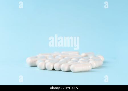 Medicine or supplement capsules on blue surface. Pharmaceutical pills, tablets and vitamins. Stock Photo