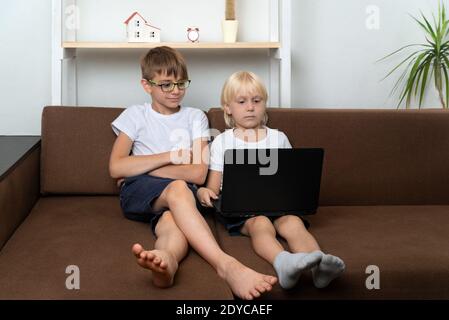 Two boys watching studying video on laptop. Children with laptops in hands. Stock Photo