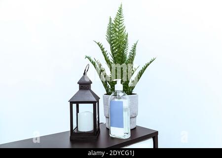 A flashlight with a candle, a green fern in a flowerpot, and a bottle of disinfectant at the front desk in the office. Stock Photo