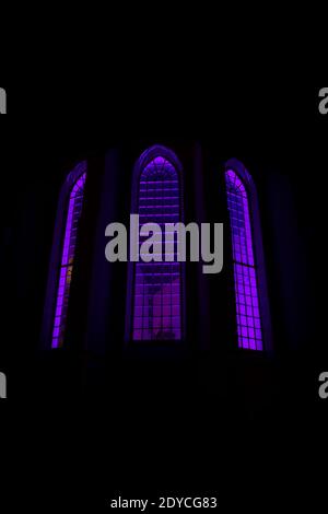 Purple backlit stained glass of dark church at night Stock Photo