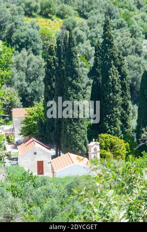 View of small white houses with a chapel, framed by dark green cypress trees. Valley in the plateaus of the Greek island of Crete. Hot but humid Stock Photo