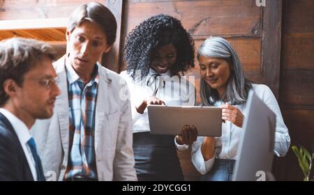 Team work of the multi ethnic group of young freelancers discuss deadline of a project concept working on desktop computer and digital pad working all Stock Photo