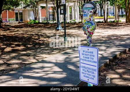 A parking meter sign encourages visitors to leave donations for the homeless instead of giving money to panhandlers in Cathedral Square in Mobile, Ala. Stock Photo