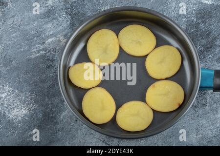 Sliced potato inside of black pan on the grey background Stock Photo