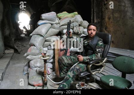 Free Syrian Army 'Al Tawhid' brigade member seen with a waterpipe or narguileh in the old market (souk) next to the Great Mosque or the Umayyad Mosque, in the center of Aleppo, Syria, on March 16, 2013. The mosque was built in the beginning of the 8th century. And its most 'recent' part was achieved in 1090. The prophet Zacharie's shrine is located inside. The mosque has been partly burned and destroyed during the fights. Photo by Ammar Abd Rabbo/ABACAPRESS.COM Stock Photo