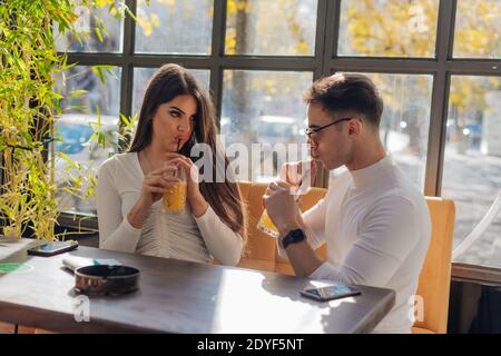 Friends socializing, having fun, and laughing drinking coffee in coffeehouse while fooling around. Male and female friends Taking pictures together on Stock Photo