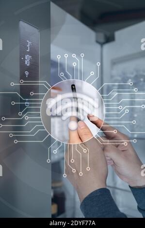 The hand of the man who controls the refrigerator with his smartphone. Internet of Things Concept Stock Photo
