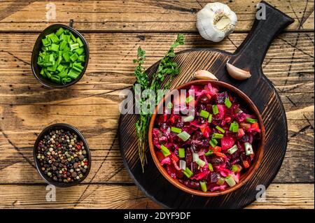 Traditional russian salad vinaigrette with boiled vegetables, pickled cucumbers in bowl . Wooden background. Top view Stock Photo