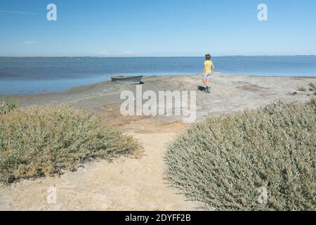 Little boy in a yellow shirt strollingin  in the arid land of Camargue region of France during a sunny day Stock Photo