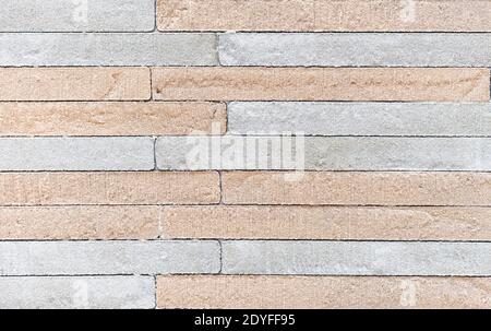 Texture of a rough stone wall made of gray and beige rectangular blocks. Stock Photo